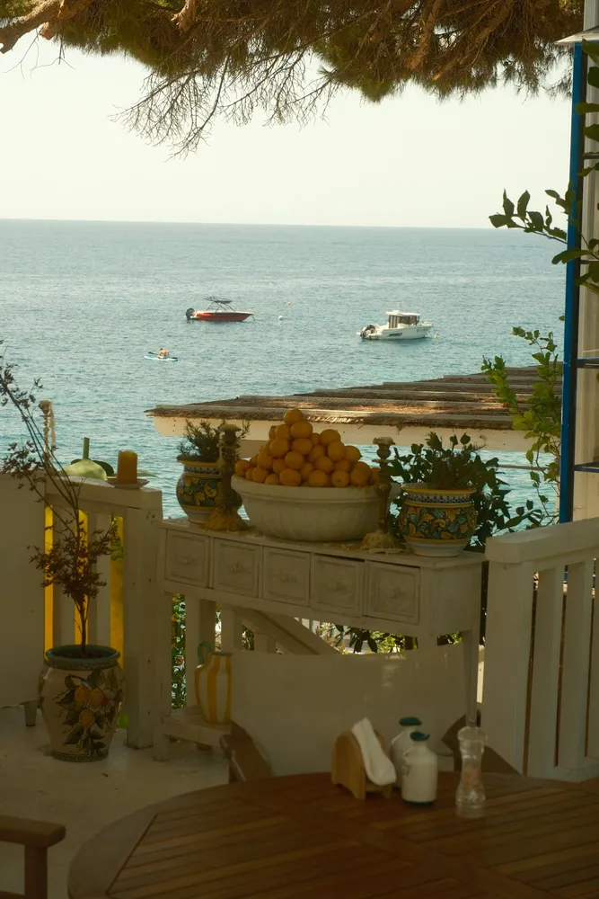 Un cuenco de limones sobre una mesa blanca frente al mar